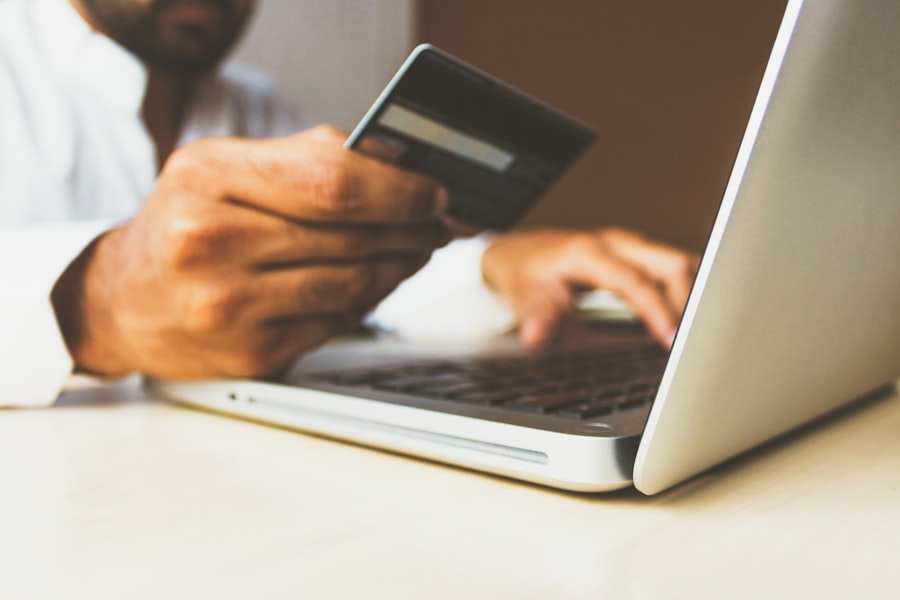 Hand holding a credit card while typing on a laptop, representing the Franchise Ops Companion App project