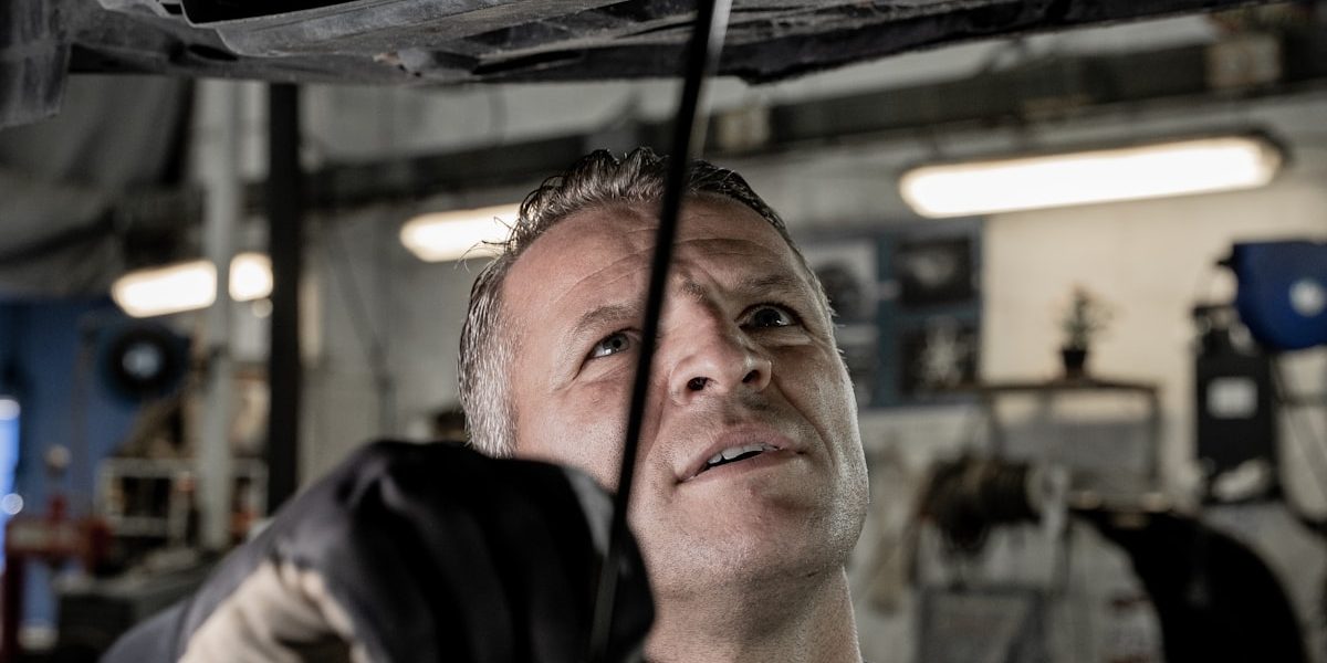 Mechanic working under a car hood in a workshop, representing the Garage Inventory and Workshop Management SaaS project