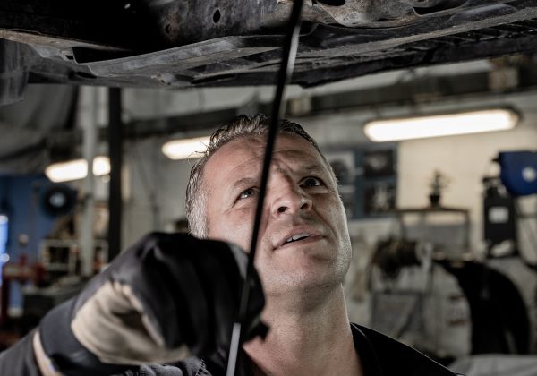 Mechanic working under a car hood in a workshop, representing the Garage Inventory and Workshop Management SaaS project