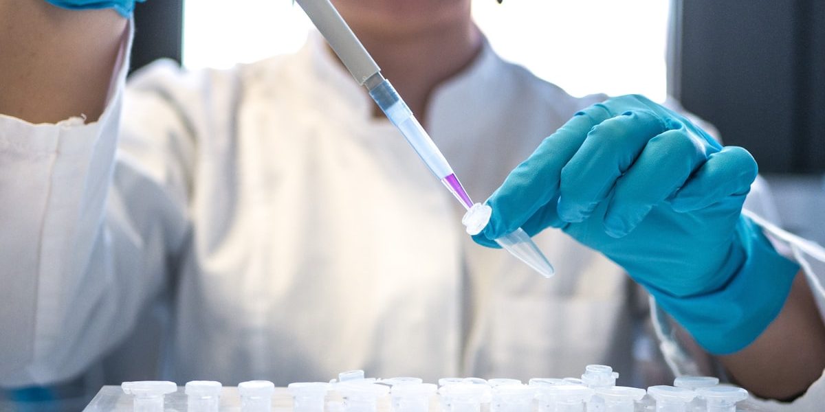 Lab scientist in gloves handling test tubes, representing the Life Sciences Corporate Website project