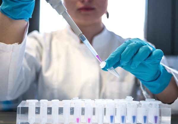 Lab scientist in gloves handling test tubes, representing the Life Sciences Corporate Website project